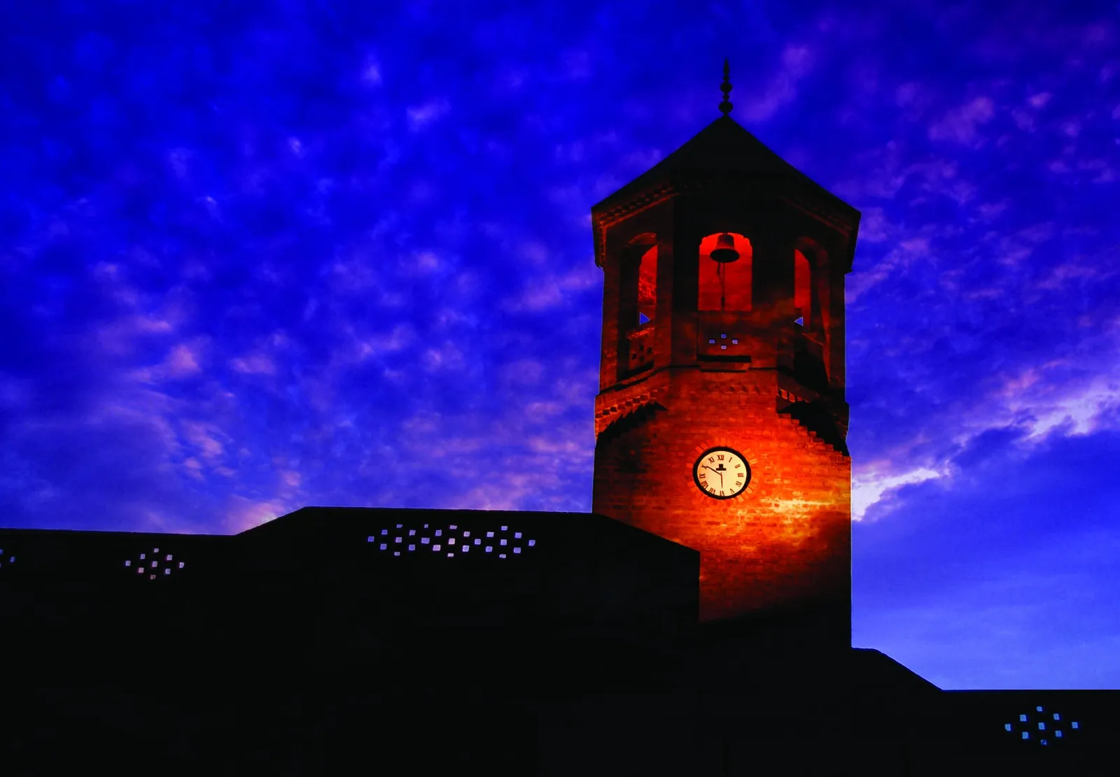 The Chand Bagh clock tower at dusk, lit against an evening sky.
